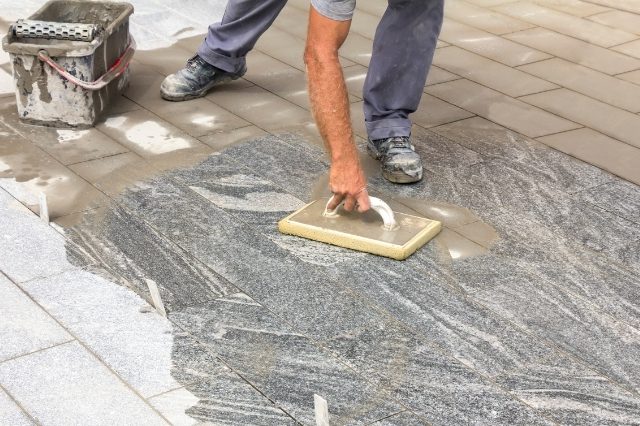 worker applying waterproofing on tiles