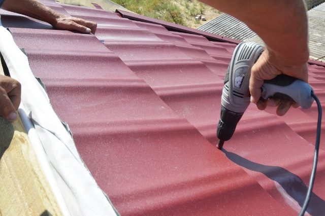 a worker drilling roof panels