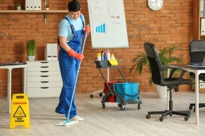 a janitor in blue coverall mopping wooden floor of an office